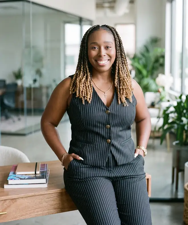 Desiree Whitehead, founder and CEO of Howl Marketing, leaning on a desk in a modern office